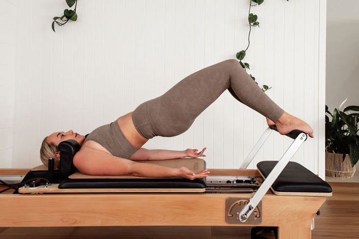 A person stretching on a reformer Pilates machine
